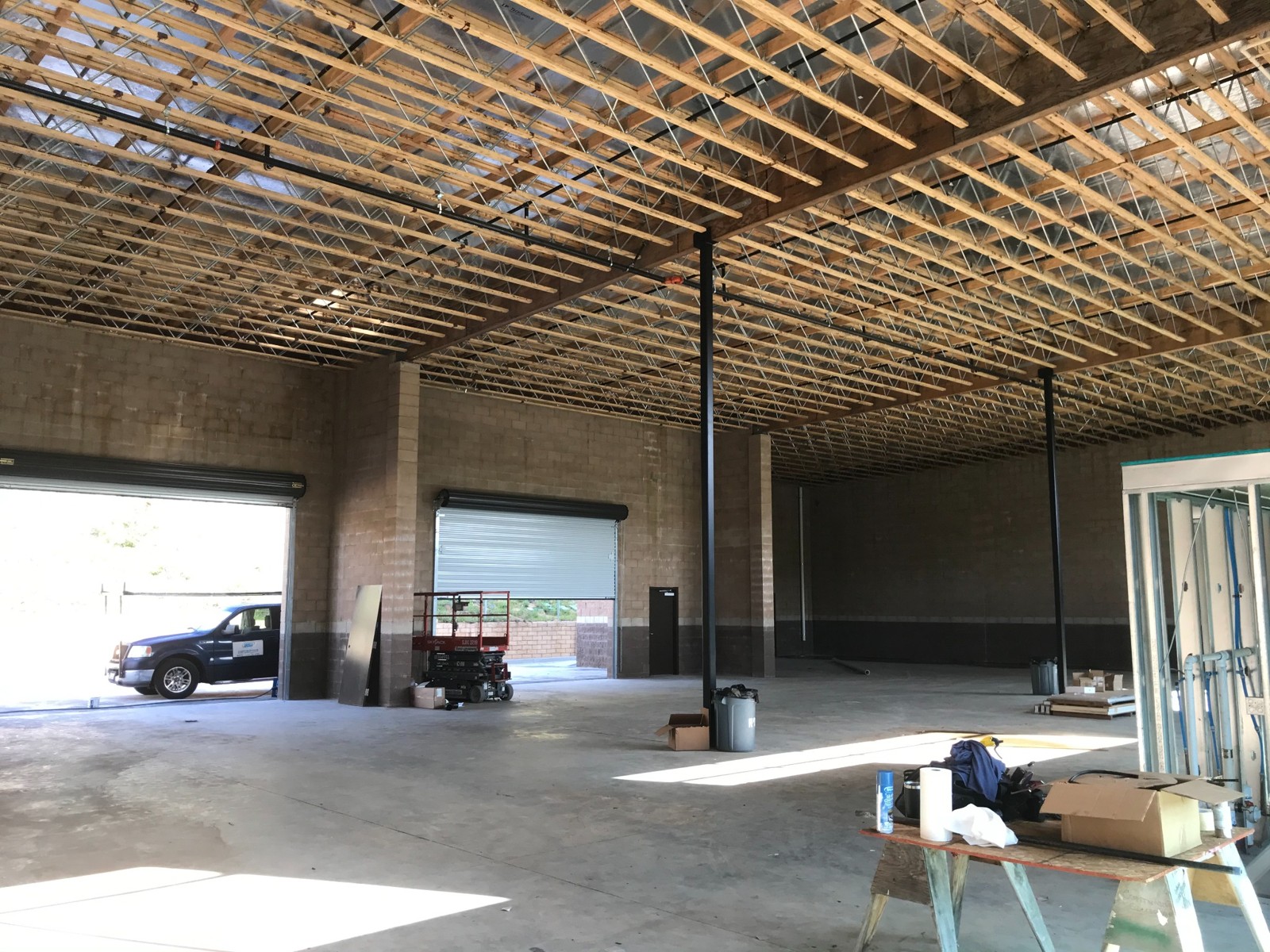 Interior of El Cajon Light Manufacturing building during construction, showing roof framing and masonry walls