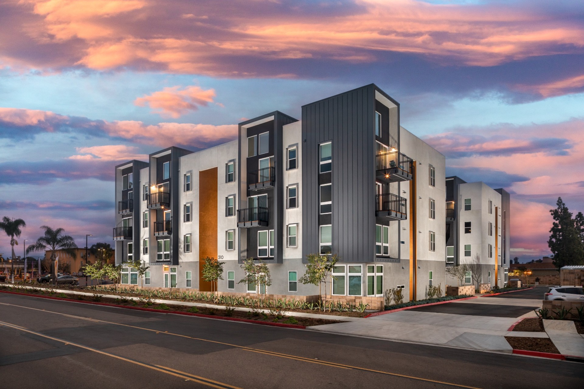 Full exterior of the completed four story K Street Apartments building at sunset